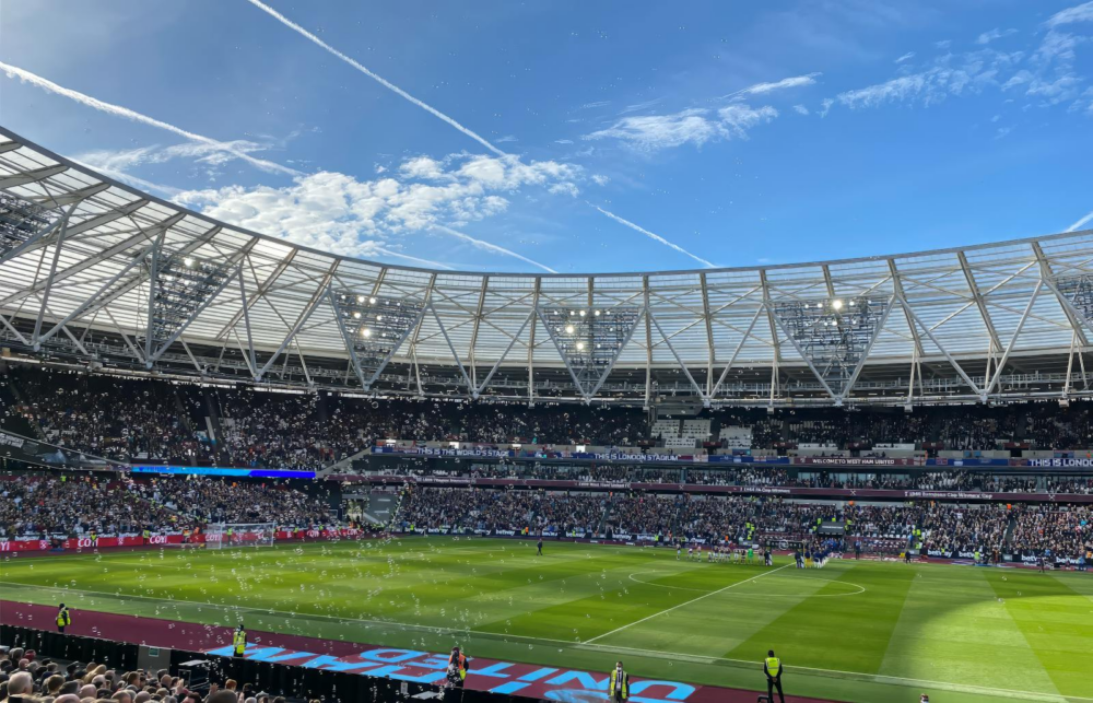 A packed London Stadium hosts a thrilling soccer match, with vibrant atmosphere and engaged crowd.