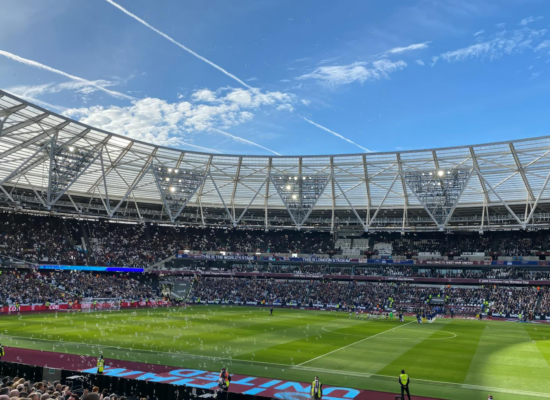 A packed London Stadium hosts a thrilling soccer match, with vibrant atmosphere and engaged crowd.